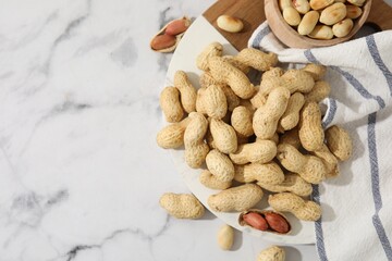 Fresh peanuts on white marble table, flat lay. Space for text