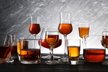 Different delicious liqueurs in glasses on dark wooden table
