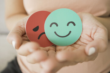 Middle age woman hands holding sad face hiding behind happy face, bipolar and depression, mental...