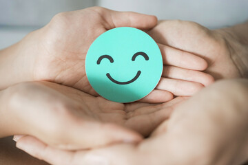 Hand holding green happy smile face paper cut, mental health assessment, child positive wellness,...
