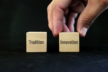 Hand choosing innovation over tradition concept. Wooden blocks on black background.