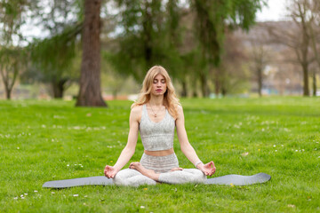 Woman meditating in lotus pose on grass in park