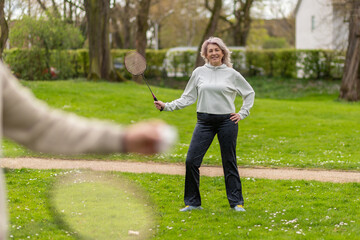 Woman with badminton racket standing in park near a man in the foreground
