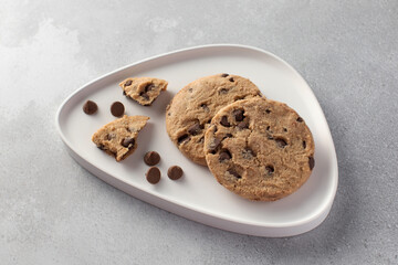 Chocolate chip cookies on a modern plate with a gray background. 