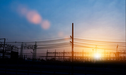 Silhouette of electricity transmission pylon at sunset sky. High voltage electric transmission tower.