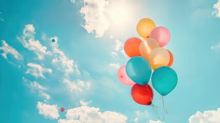 multiple colorful balloons flying on a blue sky with white clouds