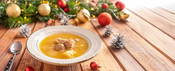 A bowl of sopa de galets, a traditional spanish christmas soup dish on a table with christmas decorations, copy space
