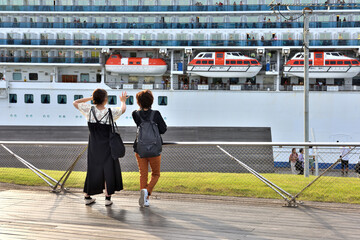桟橋から大型客船の出向を見送る人達