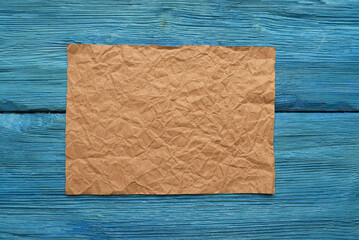 Blank brown crumpled paper page on the blue flat lay desk table background with copy space. Retro...