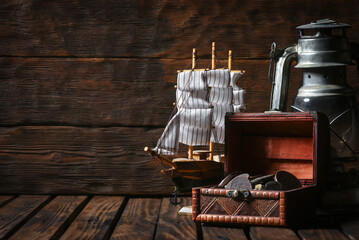Sea travel or piracy concept background. Sea ship boat, old coins and compass on the wooden desk...