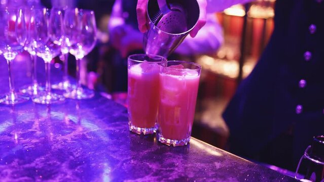 Bartender working, beautiful row line of different coloured liquor alcohol cocktails on a party in a bar, and others on catering banquet on event, barman mixing drinks and beverages in a club
