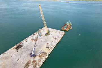 Aerial view of a new berth being constructed at the bustling Port of Cebu, featuring cranes, workers, and marine equipment.
