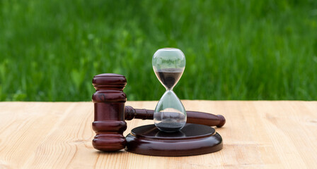 Judge's gavel and hourglass on grass background