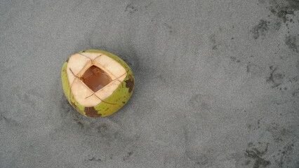 Coconuts on the beach sand. There's just a little coconut water left