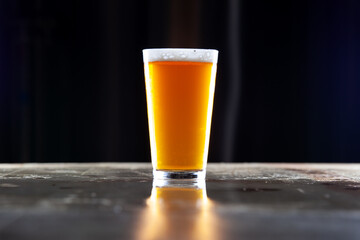 Perfectly poured fresh golden ale beer in a pint glass on a bar top counter with a perfect foamy head. 