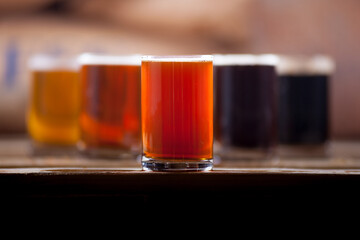 Beer sampler collection in standard 4 ounce glasses with a red ale in the foreground of other...