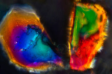 Two bright grains of California sand glow with polarization microscopy.