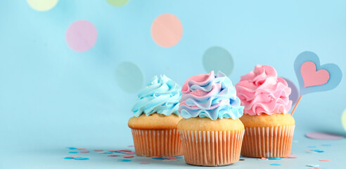 Delicious cupcakes with decor on blue background. Gender reveal party concept