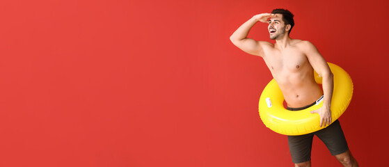 Handsome man with inflatable ring on color background