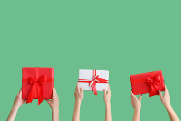 Female hands holding Christmas gift boxes on green background