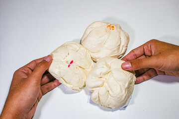 three white buns served on a plain white background and held in two hands