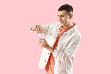 Young man opening tasty yogurt on pink background