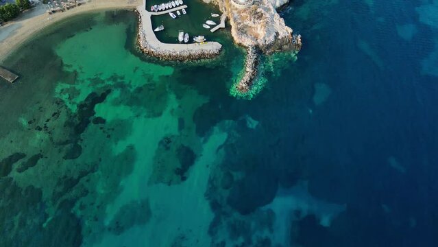 Aerial footage of a small little port with a picturesque windmill in the town of Parikia, on the island of Paros, one of the many Cyclades Islands in the Aegean Sea.