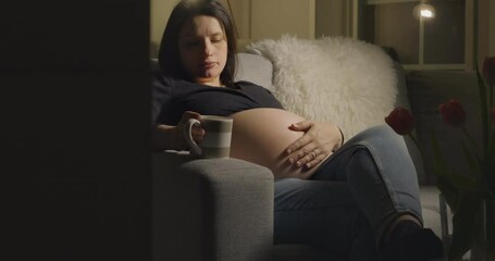 Pregnant expecting woman preparing mentally for labour in sofa at night