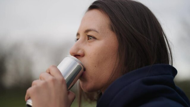 Attractive caucasian female brunette drink beverage from aluminium can