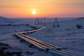 Winter arctic industrial landscape. View of a pipeline and electrical towers in the snowy tundra of...