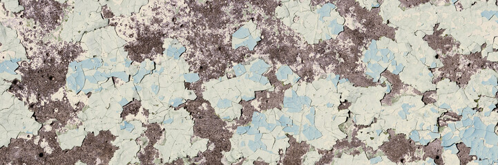 Peeling paint on the wall. Panorama of a concrete wall with old cracked flaking paint. Weathered rough painted surface with patterns of cracks and peeling. Wide panoramic grungy texture for background
