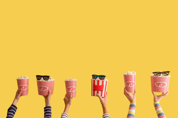 Many hands with buckets of popcorn and 3D glasses on yellow background
