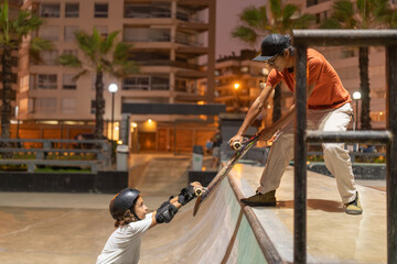 Coach helping his skateboarding student up the ramp at the skate park