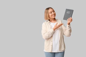 Happy adult woman pointing at Holy Bible on white background