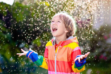 Child playing in autumn rain. Kid with umbrella.