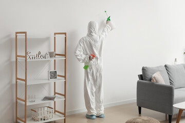 Female worker of cleaning service removing mold from wall in room, back view