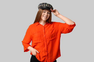 Stylish young girl in hat and shirt on light background