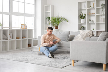 Young bearded man using tablet computer on floor at home