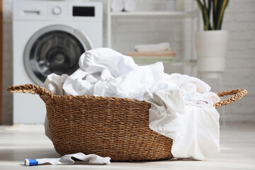 Laundry basket with white clothes in room, closeup