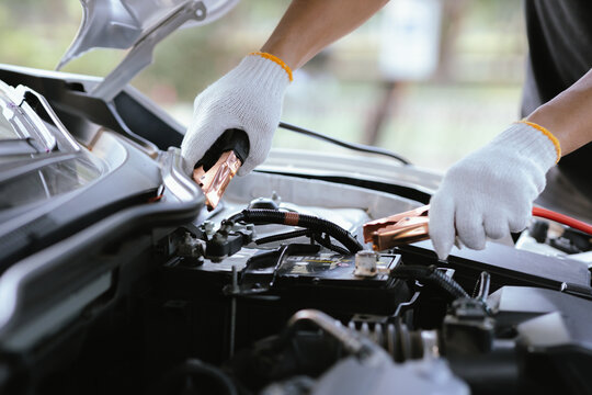 Close-up of auto mechanic charging car battery with electric rail jumper cables - Powered by Adobe