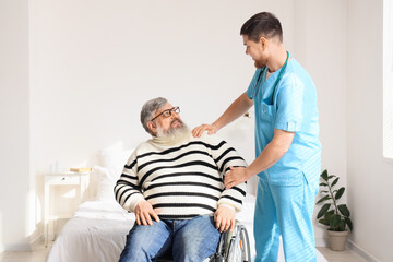 Senior man in wheelchair with caregiver smiling at home