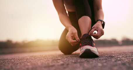 Running shoes, closeup of woman tying shoe laces. Female sport fitness runner getting ready for jogging outdoors
