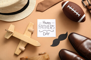 Paper with text HAPPY FATHER'S DAY and accessories on brown background. Top view