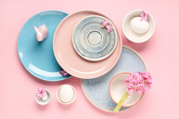 Stylish table setting with Easter eggs, flowers and toy bunny on pink background