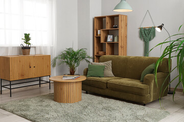 Interior of stylish living room with green sofa, table and drawers