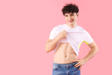 Handsome young happy sporty man on pink background. Weight loss concept