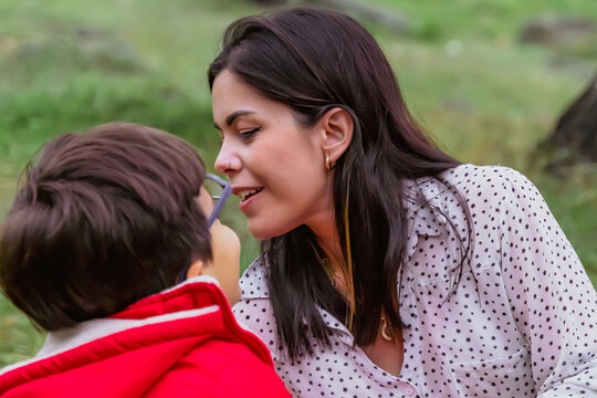International Children Day. Latin mother having fun with her young children outdoors. Sitting on the ground playing with their hands. Concept of family. Single mother with two young children.