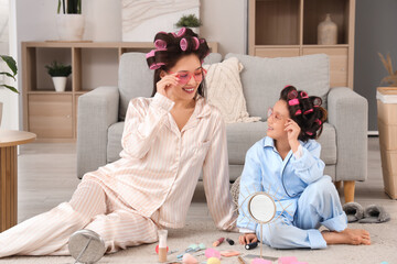 Little Asian girl and her mother in sunglasses with hair curlers at home