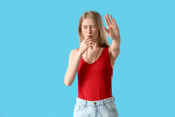 Young female lifeguard whistling on blue background