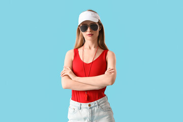 Young pretty female lifeguard in sunglasses with crossed arms on blue background